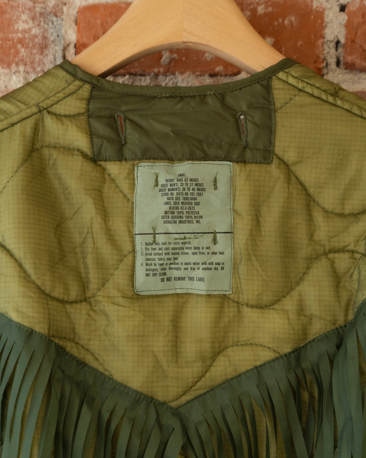Closeup of vintage inner tag that reads size small. Height: Over 63 inches; Chest Men's: 33 to 37 inches; Chest Women's: 36 to 40 inches. Wash by hand or machine in warm water with mild soap or detergent, rinse thoroughly and drip or machine dry. DO NOT DRY CLEAN.