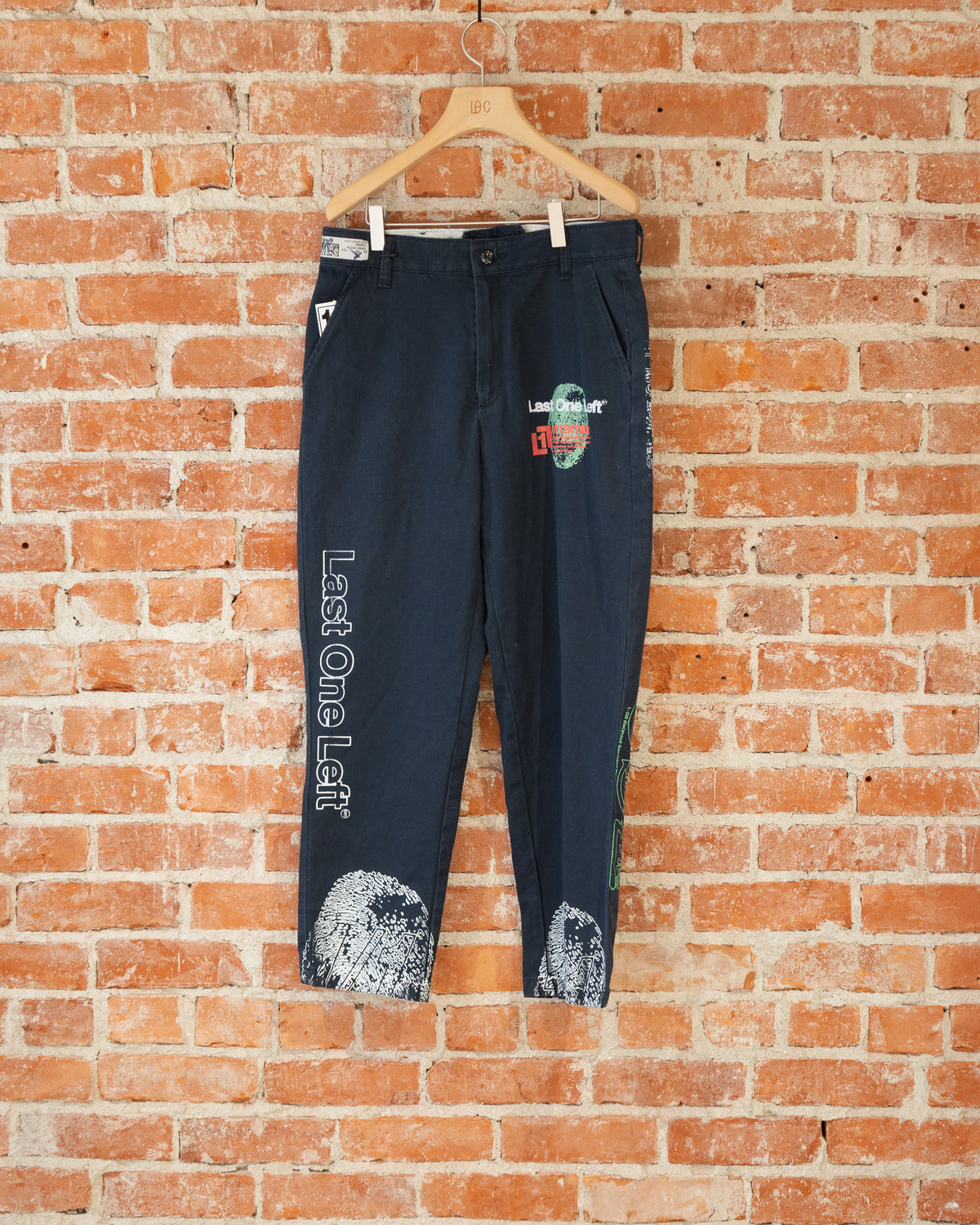 Navy vintage pants with white, green, and orange screenprinted designs on them.