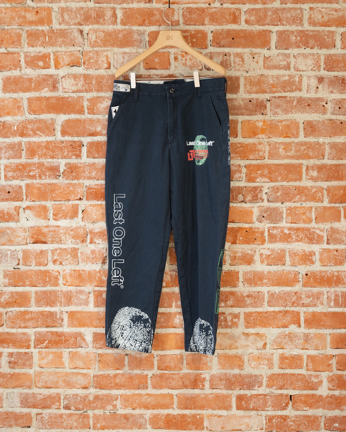 Navy vintage pants with white, green, and orange screenprinted designs on them.