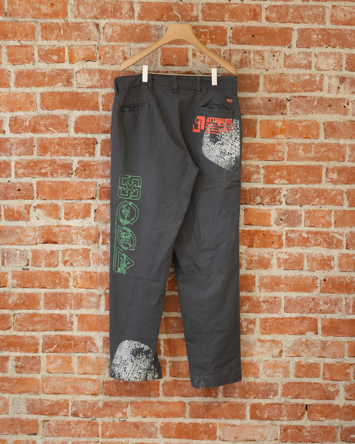 Black vintage pants with multicolored screenprinted designs on them.