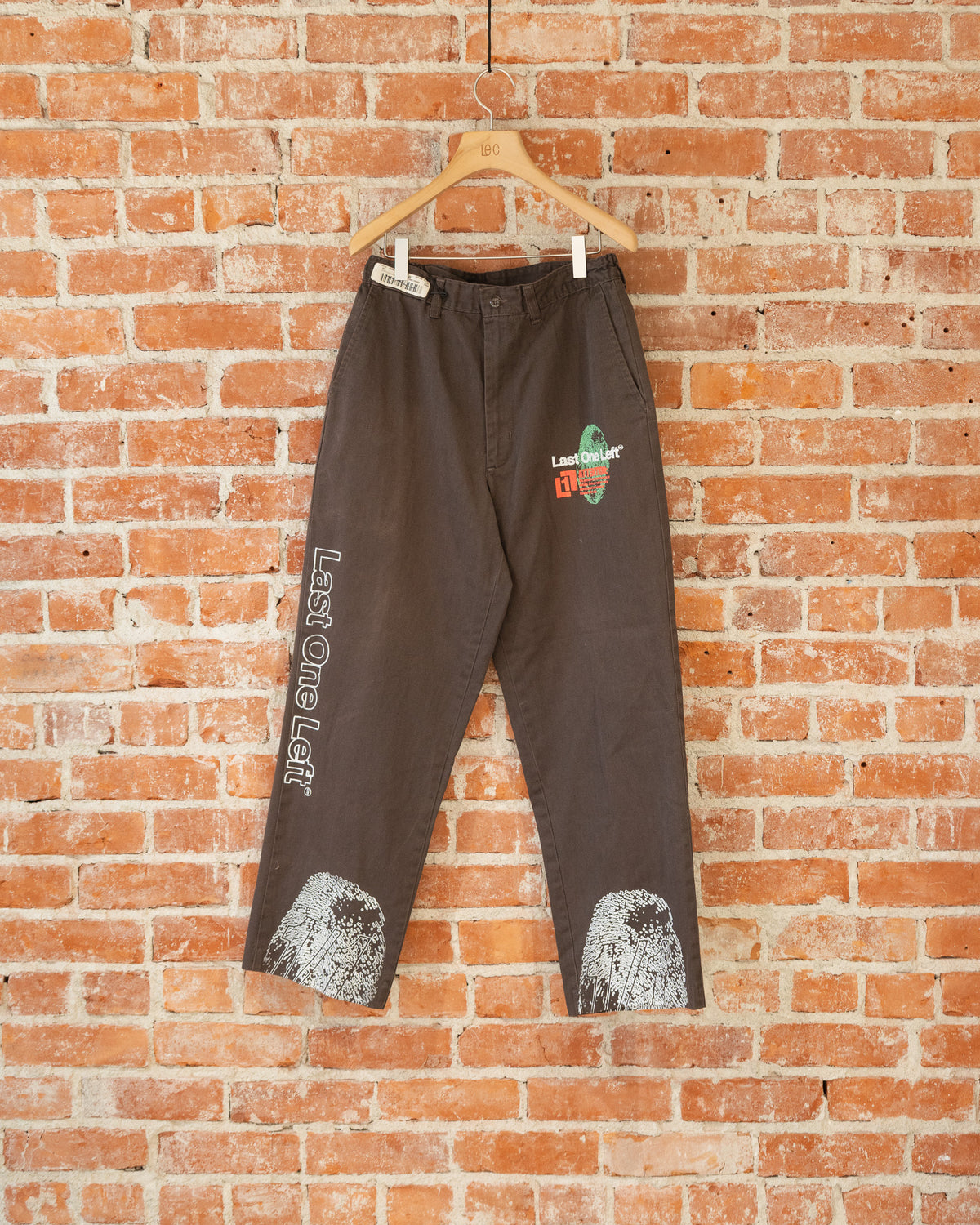 Brown vintage pants with multicolored screenprinted designs on them.
