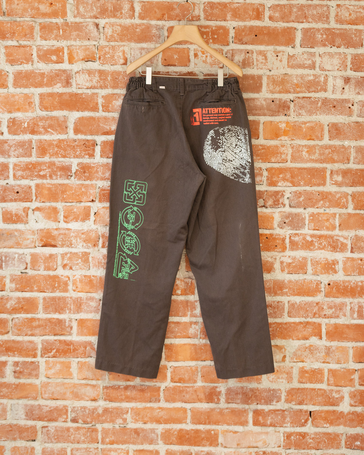 Brown vintage pants with multicolored screenprinted designs on them.
