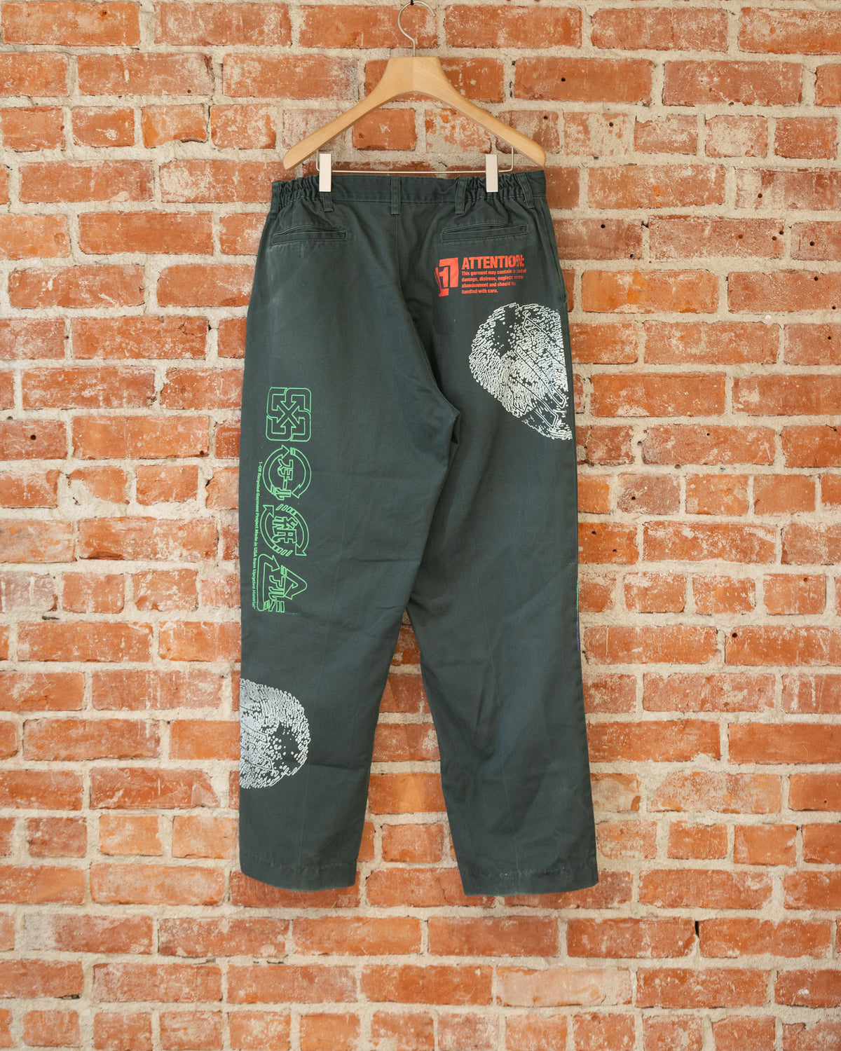 Green vintage pants with multicolored screenprinted designs on them.