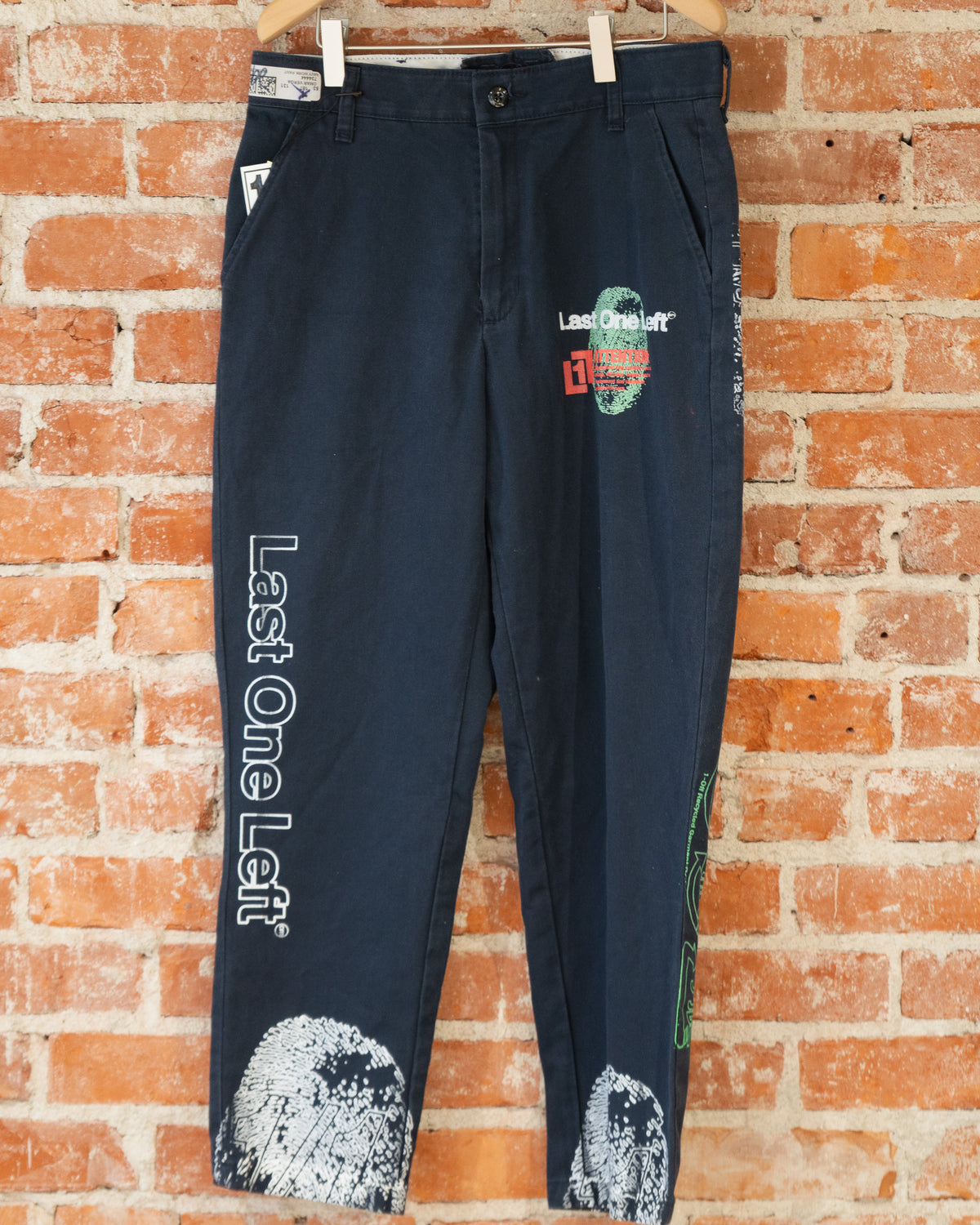 Navy vintage pants with white, green, and orange screenprinted designs on them.
