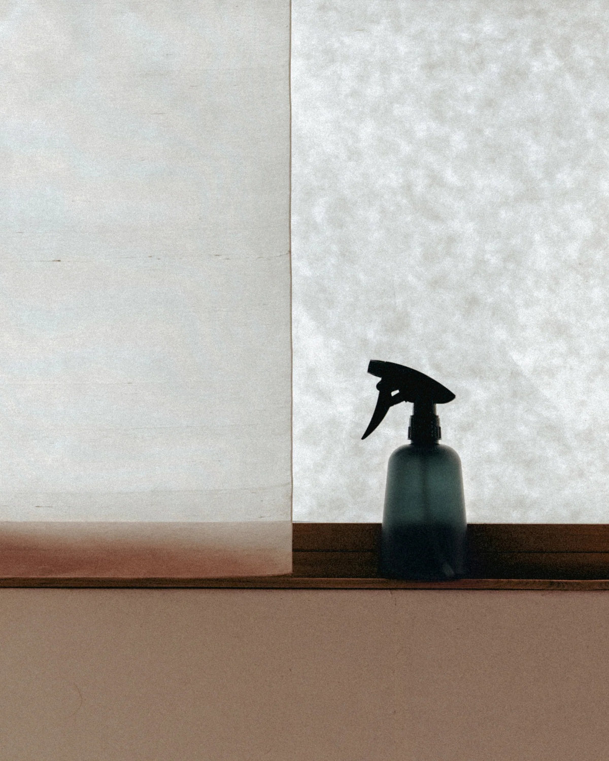 hinok The Spray bottle in front of a window with light curtains.