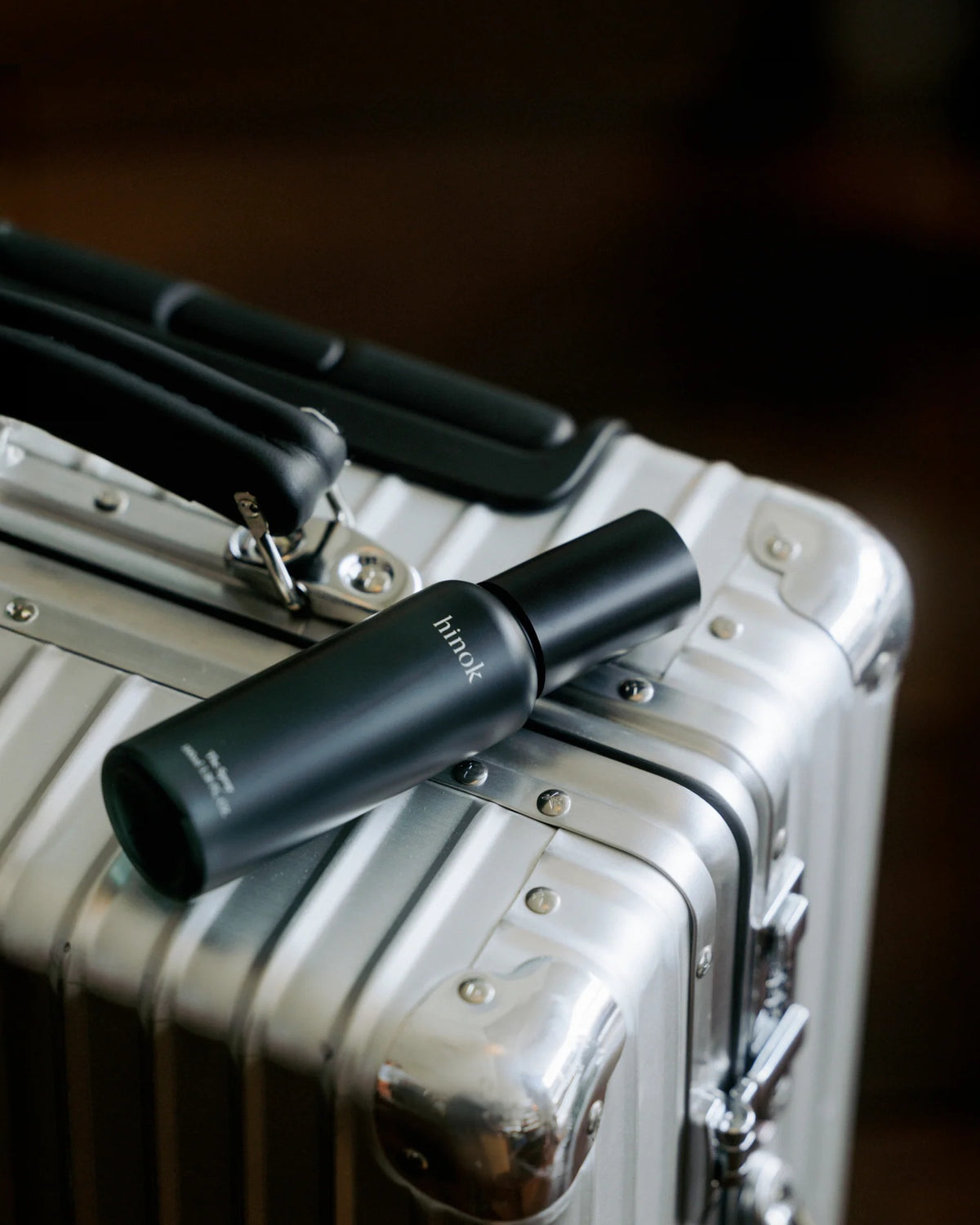 hinok The Spray in travel size on top of a suitcase.