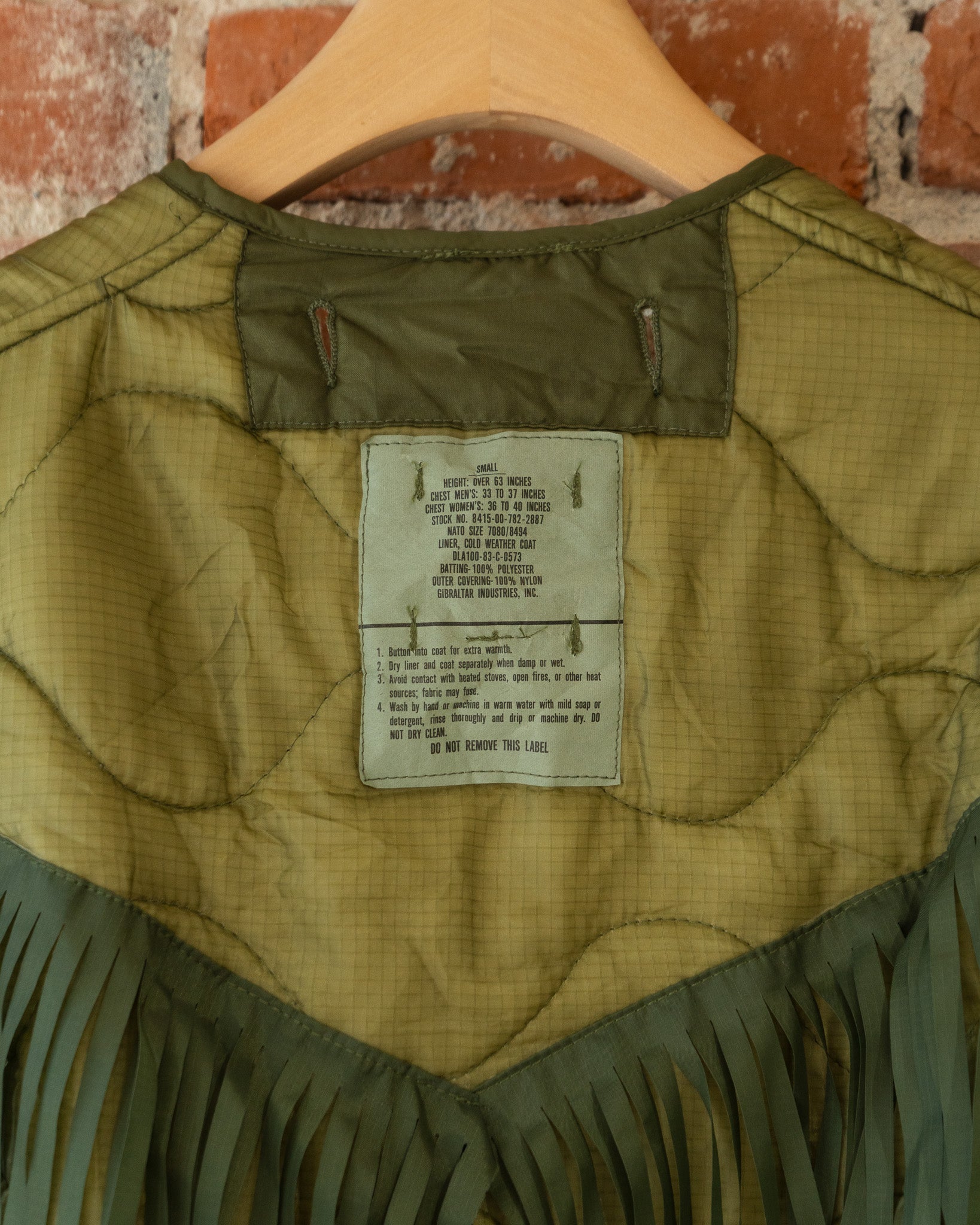 Closeup of vintage inner tag that reads size small. Height: Over 63 inches; Chest Men's: 33 to 37 inches; Chest Women's: 36 to 40 inches. Wash by hand or machine in warm water with mild soap or detergent, rinse thoroughly and drip or machine dry. DO NOT DRY CLEAN.