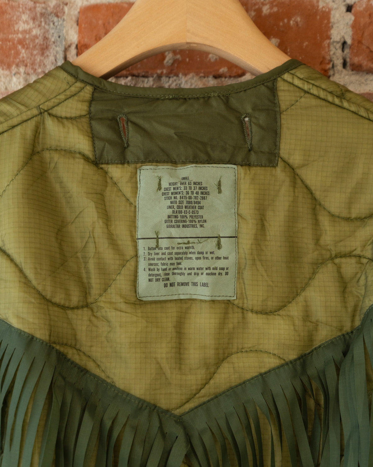 Closeup of vintage inner tag that reads size small. Height: Over 63 inches; Chest Men's: 33 to 37 inches; Chest Women's: 36 to 40 inches. Wash by hand or machine in warm water with mild soap or detergent, rinse thoroughly and drip or machine dry. DO NOT DRY CLEAN.