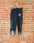 Navy vintage pants with white, green, and orange screenprinted designs on them.