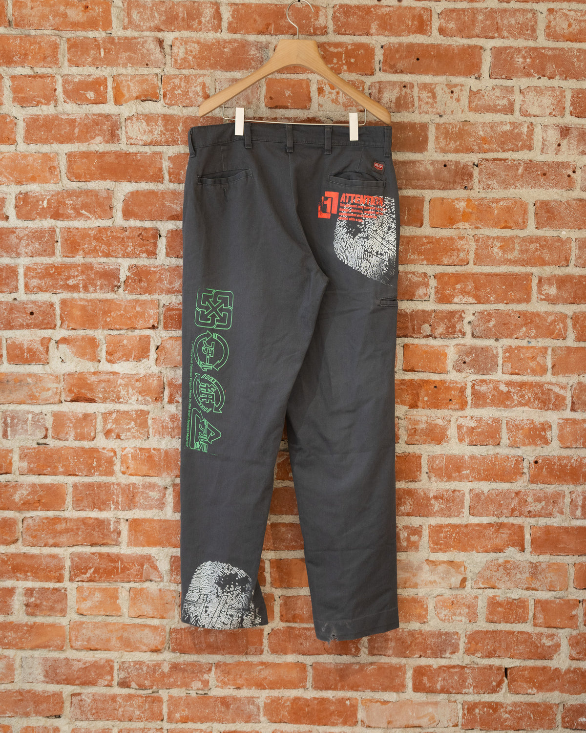 Black vintage pants with multicolored screenprinted designs on them.