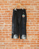 Black vintage pants with multicolored screenprinted designs on them.