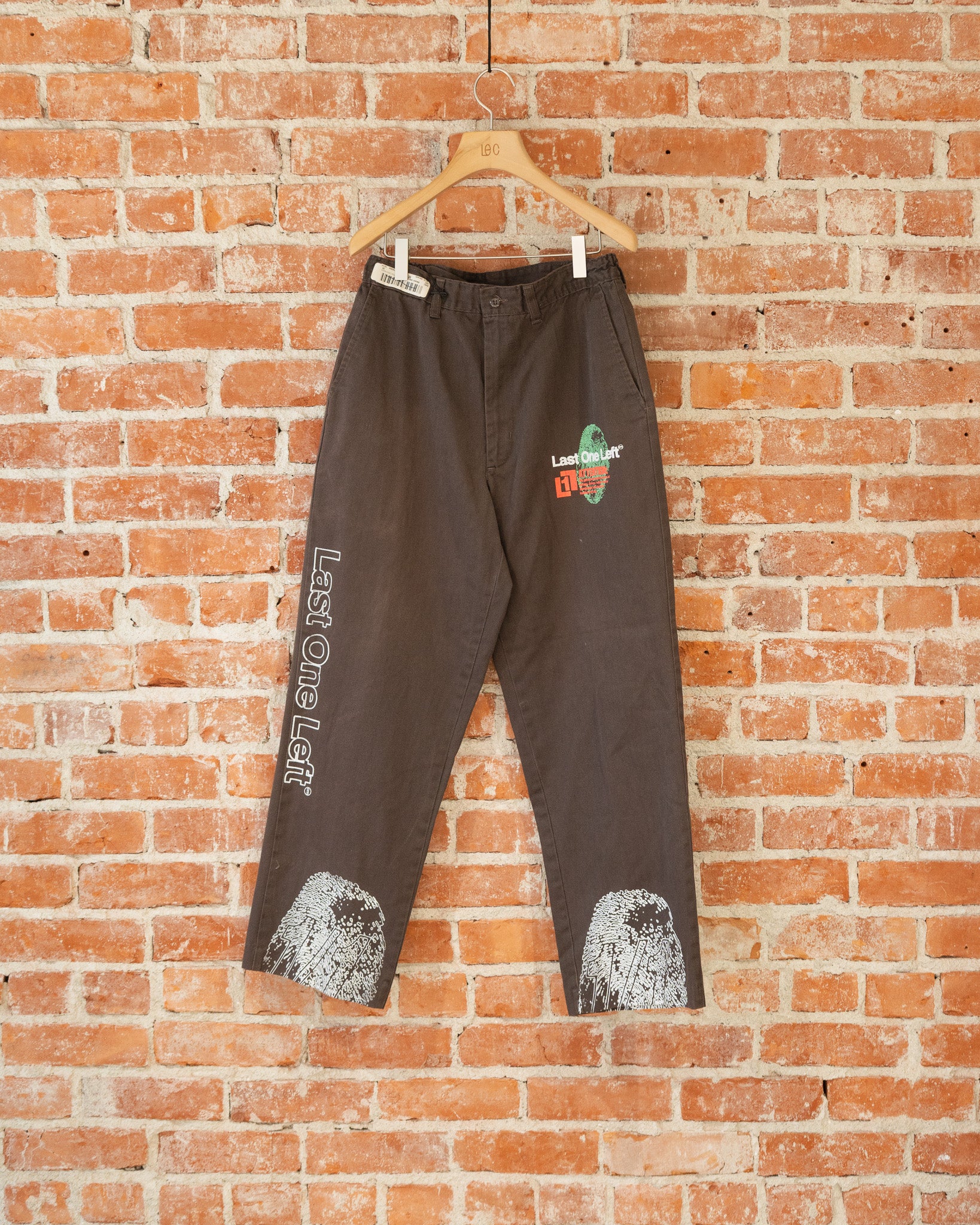 Brown vintage pants with multicolored screenprinted designs on them.