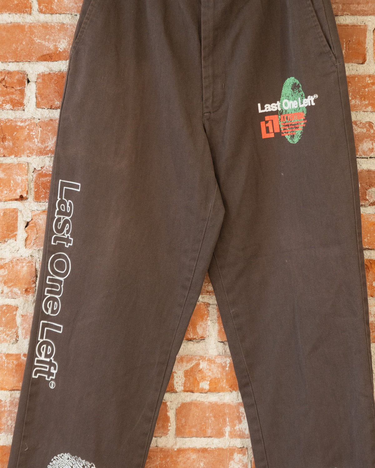 Brown vintage pants with multicolored screenprinted designs on them.