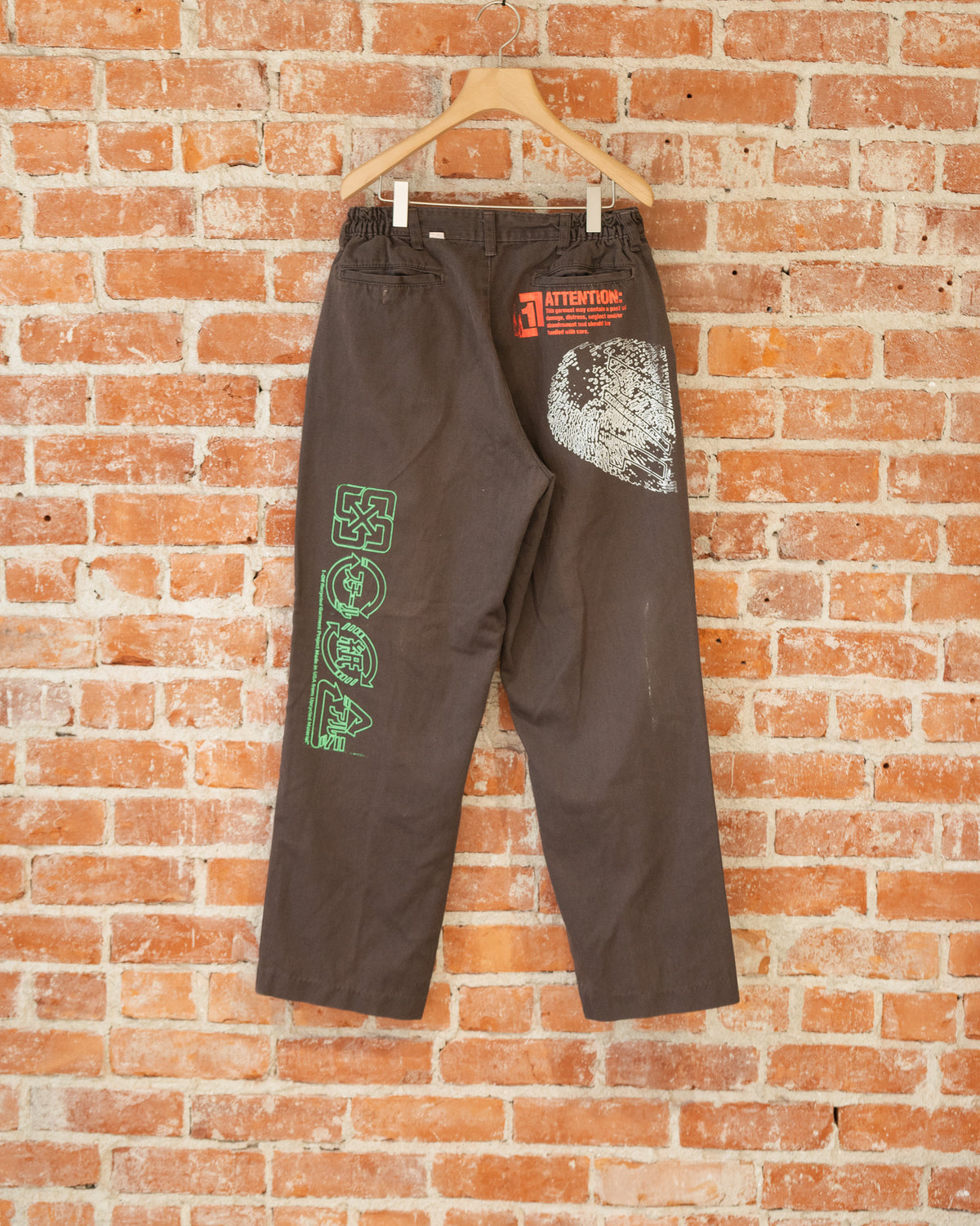 Brown vintage pants with multicolored screenprinted designs on them.