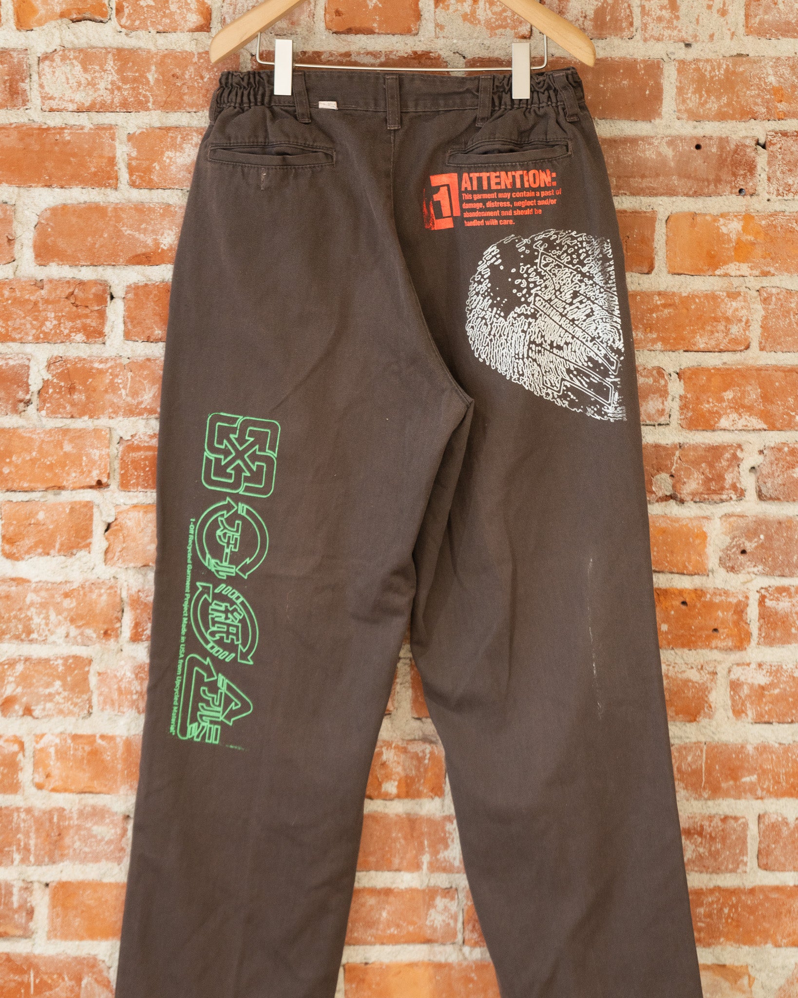 Brown vintage pants with multicolored screenprinted designs on them.