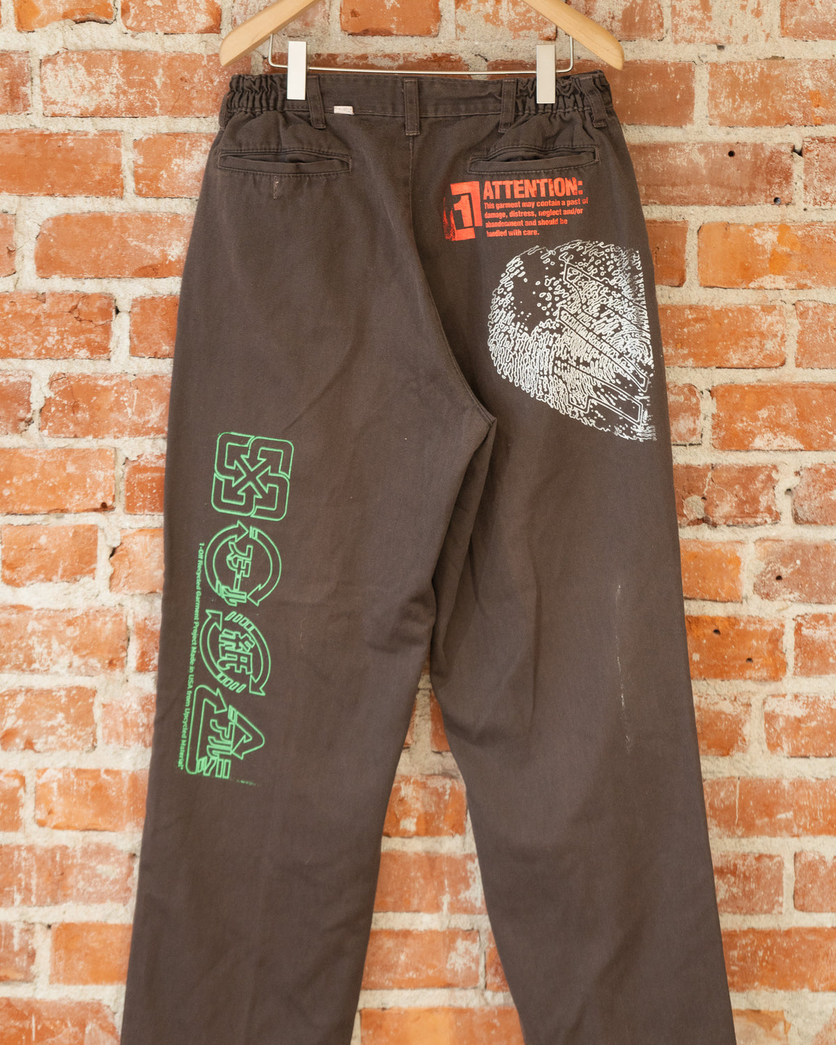 Brown vintage pants with multicolored screenprinted designs on them.