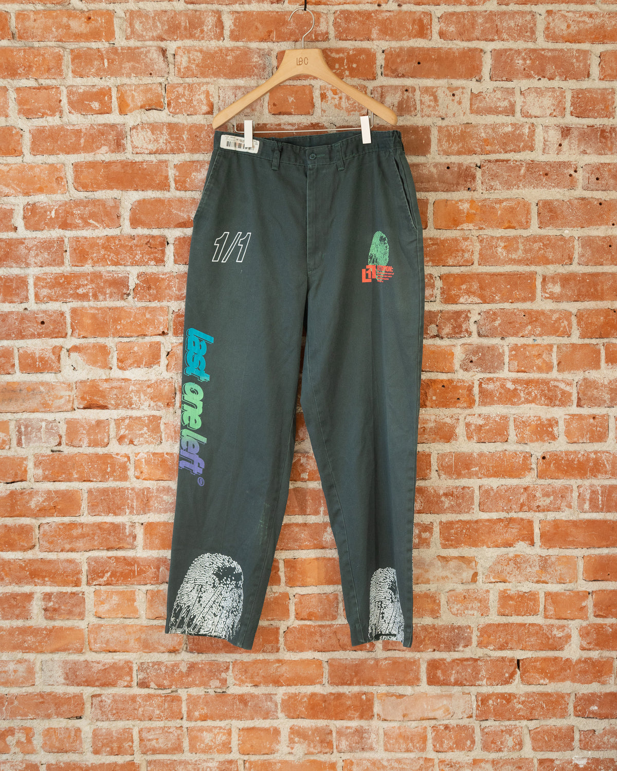 Green vintage pants with multicolored screenprinted designs on them.