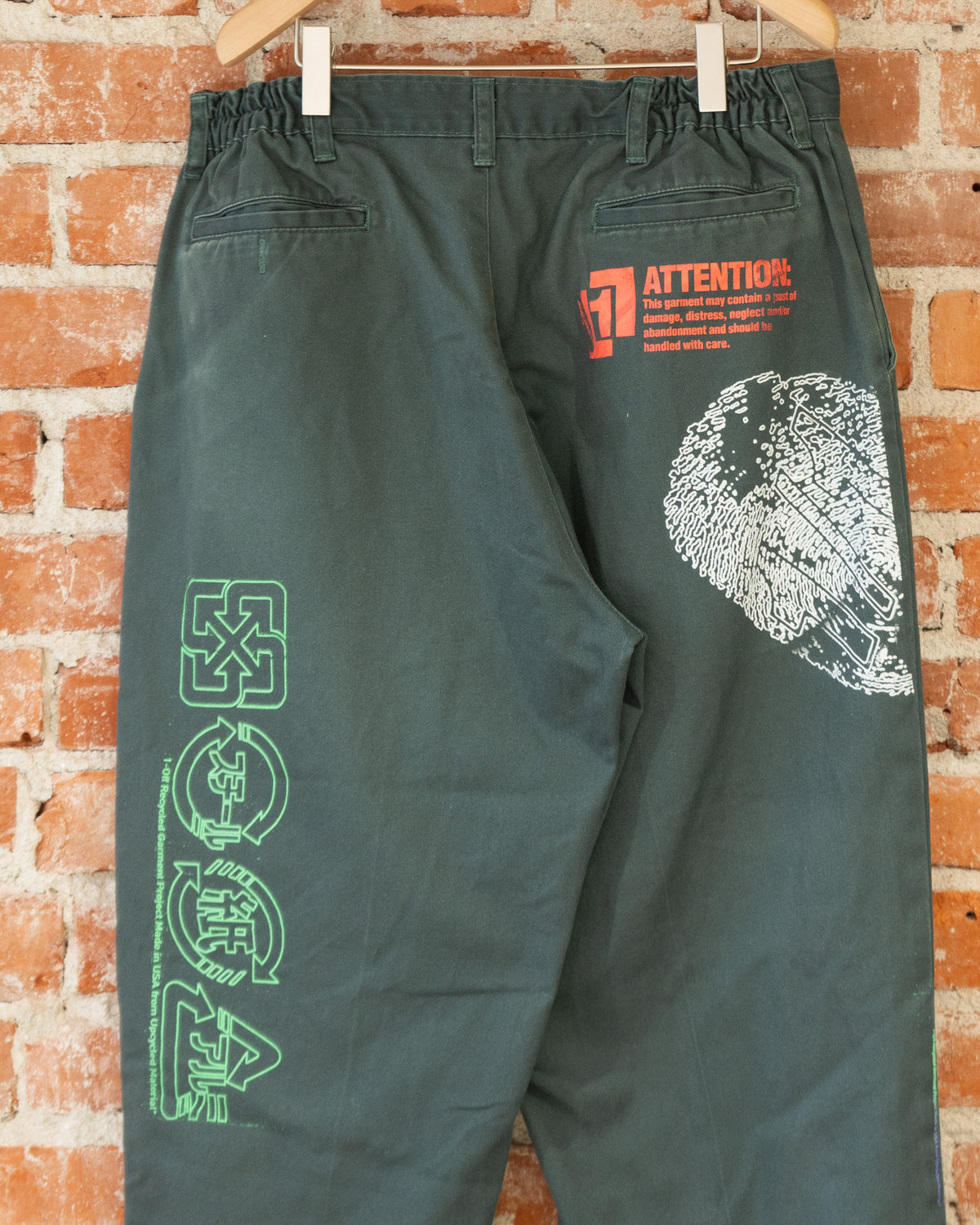Closeup of green vintage pants with multicolored screenprinted designs on them.