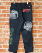 Navy vintage pants with white, green, and orange screenprinted designs on them.