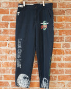 Navy vintage pants with white, green, and orange screenprinted designs on them.